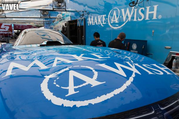 The Make A Wish Dodge body sits on the stand in the pit
