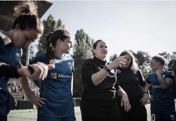 Laura Harvey (center) as defender Kendall Fletcher (left)  listens in on Harvey's coaching advice. Source: Seattle Reign FC