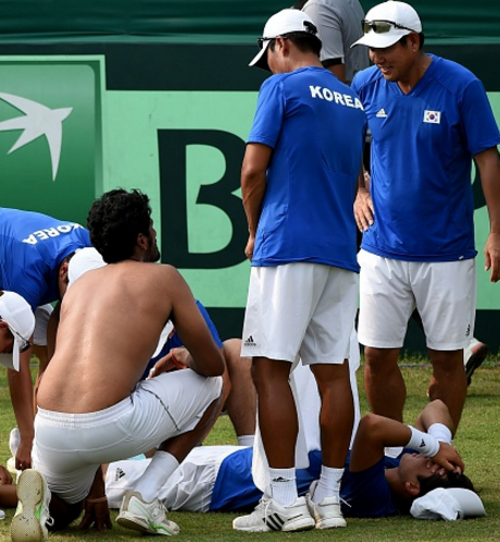 Yong-Kyu Lim lies injured after his singles rubber against Saketh Myneni (Photo by Money Sharma/AFP/Getty Images)