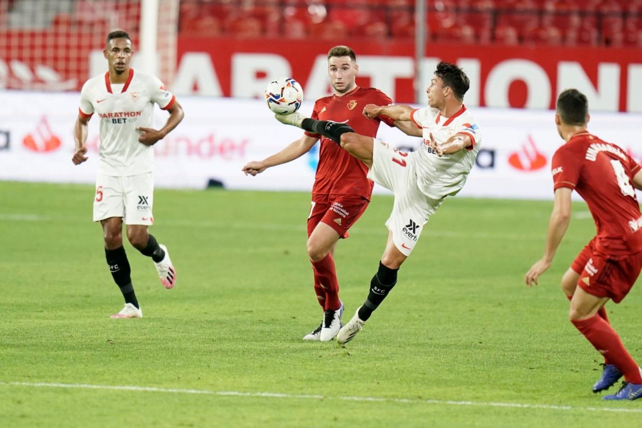 Oliver Torres trata de llevarse un balón frente a la mirada de Moncayola. Fuente: Sevilla FC