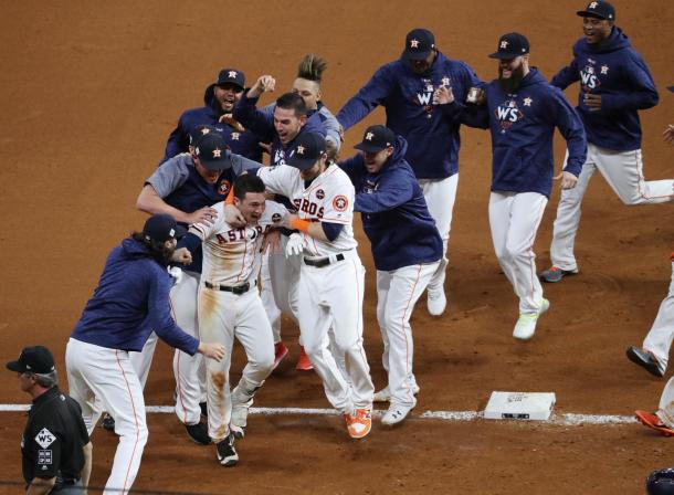 Bregman ids mobbed by teammates after driving in the winning run/Photo: Thomas Shea/Getty Images