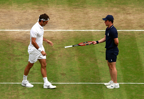 A ball-boy retrieves Roger Federer's racket following his fall. Credit: Adam Pretty/Getty Images