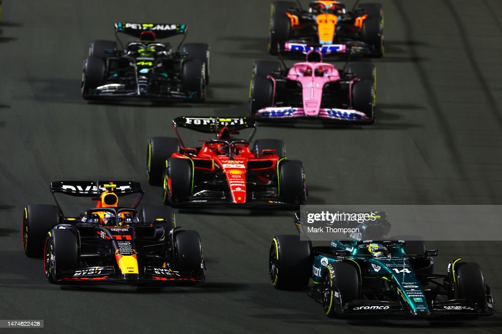 JEDDAH, SAUDI ARABIA - MARCH 19: Fernando Alonso of Spain driving the (14) Aston Martin AMR23 Mercedes leads Sergio Perez of Mexico driving the (11) Oracle Red Bull Racing RB19 and the rest of the field into turn one at the start during the F1 Grand Prix of Saudi Arabia at Jeddah Corniche Circuit on March 19, 2023 in Jeddah, Saudi Arabia. (Photo by Mark Thompson/Getty Images)