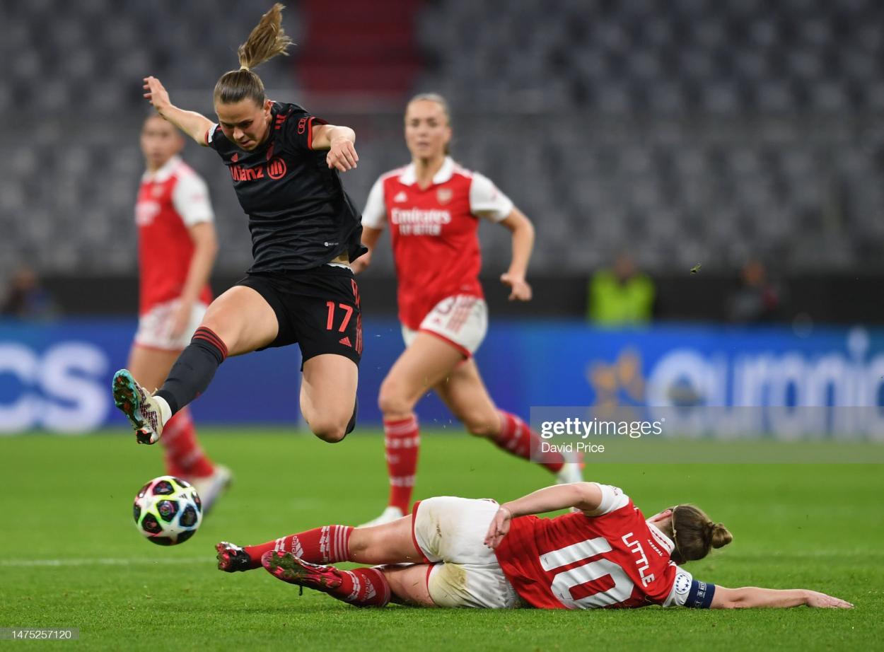 Arsenal's captain Kim Little sliding towards the ball while Bayern midfielder Klara Bühl is attempting a jump over her (Photo by David Price/Getty Images)