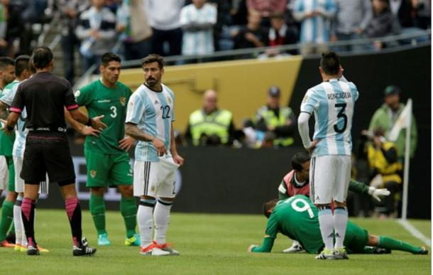 Bolivia forward Yasmani Duk (#9, on ground, in green, right) suffered a bloody nose and was replaced in the 24th minute. Photo credit: Jason Redmond/AFP