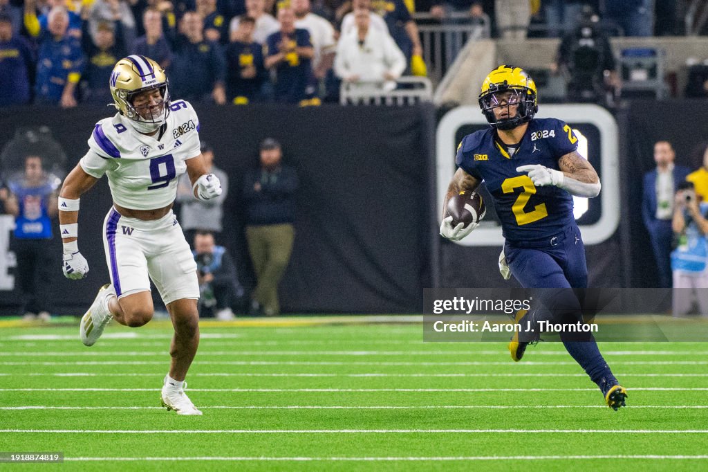 Blake Corum #2 of the Michigan Wolverines runs for yardage away from Thaddeus Dixon #9 of the Washington Huskies during the second half of the 2024 CFP National Championship game at NRG Stadium on January 08, 2024 in Houston, Texas. The Michigan Wolverines won the game 34-13. (Photo by Aaron J. Thornton/Getty Images)