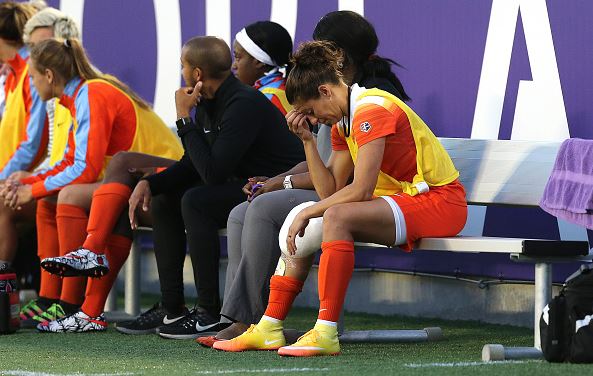 Carli Lloyd #10 of Houston Dash sits on the bench with ice on her knee during a NWSL soccer match against the Orlando Pride at the Orlando Citrus Bowl on April 23, 2016 in Orlando, Florida | Alex Menendez - Getty Images