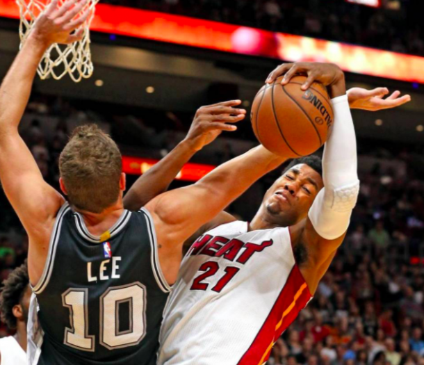 Hassan Whiteside (21) gets tangled with Spurs forward David Lee (Charles Trainor Jr./Miami Herald)