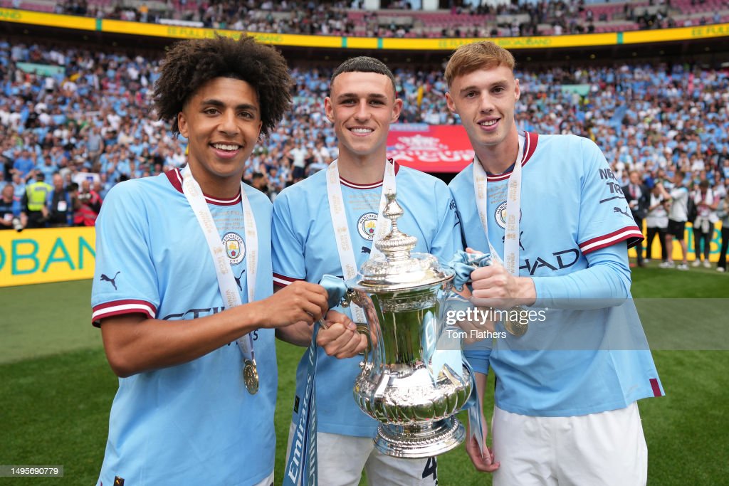 Rico Lewis, Phil Foden and Cole Palmer of Manchester City celebrate with the Emirates FA Cup trophy after the team's victory following the Emirates FA Cup Final between Manchester City and Manchester United (Photo by Tom Flathers/Manchester City FC via Getty Images)