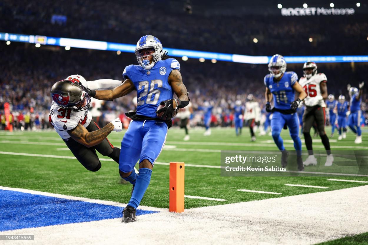 Jahmyr Gibbs #26 of the Detroit Lions stiff arms Antoine Winfield Jr. #31 of the Tampa Bay Buccaneers while scoring a touchdown during the fourth quarter of an NFL divisional round playoff football game at Ford Field on January 21, 2024 in Detroit, Michigan. (Photo by Kevin Sabitus/Getty Images)