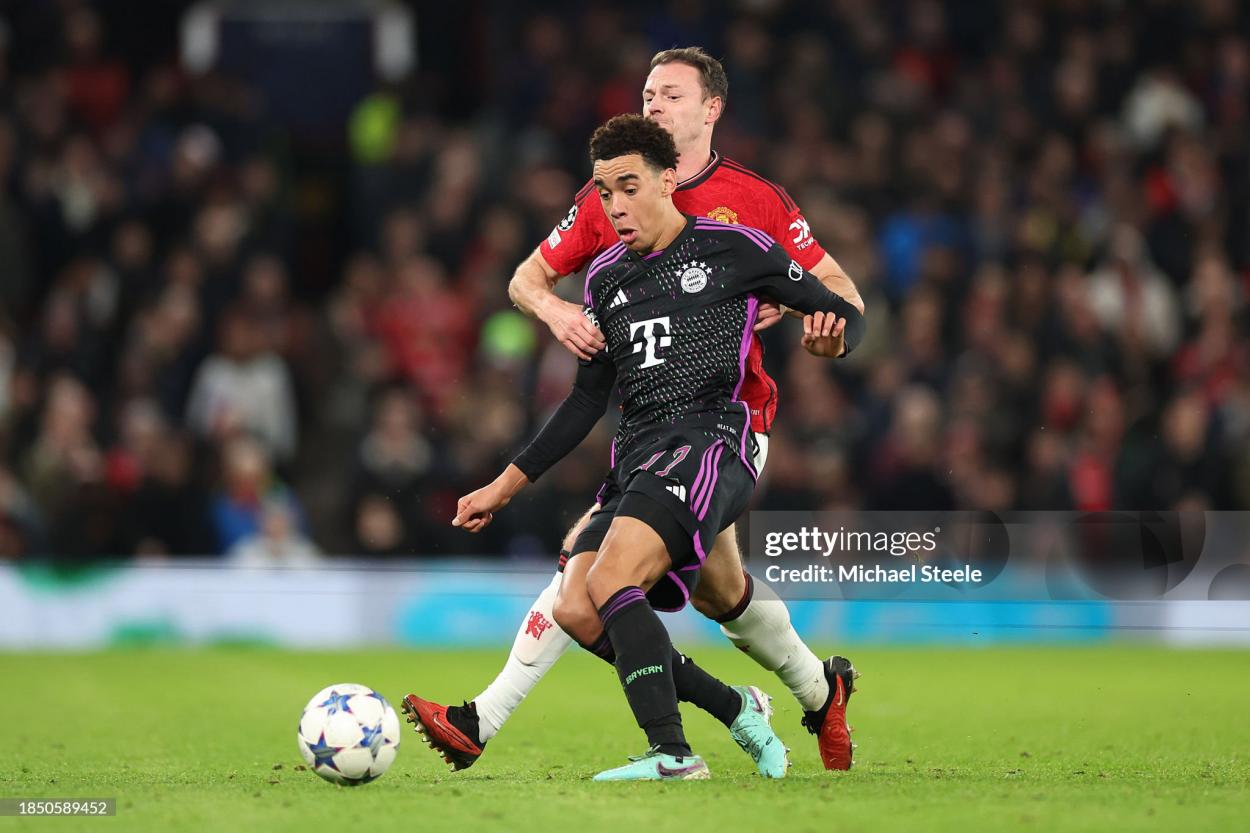 Jamal Musiala of Bayern Munich on the ball whilst under pressure from Jonny Evans of Manchester United during the UEFA Champions League match between Manchester United and FC Bayern München at Old Trafford on December 12, 2023 in Manchester, England. (Photo by Michael Steele/Getty Images)