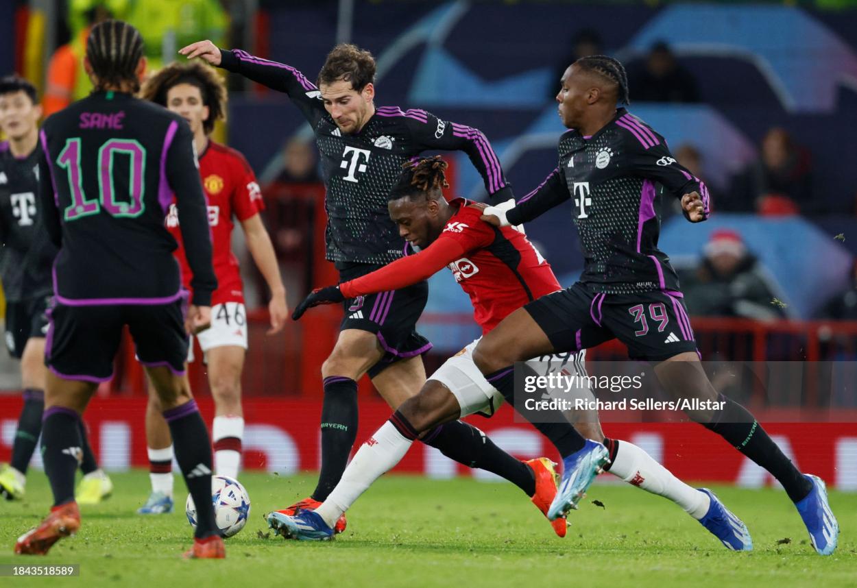 Aaron Wan-Bissaka of Manchester United is tackled by Leon Goretzka and Mathys Tel of Bayern Munich during the UEFA Champions League match between Manchester United and FC Bayern Munchen at Old Trafford on December 12, 2023 in Manchester, England. (Photo by Richard Sellers/Sportsphoto/Allstar via Getty Images)