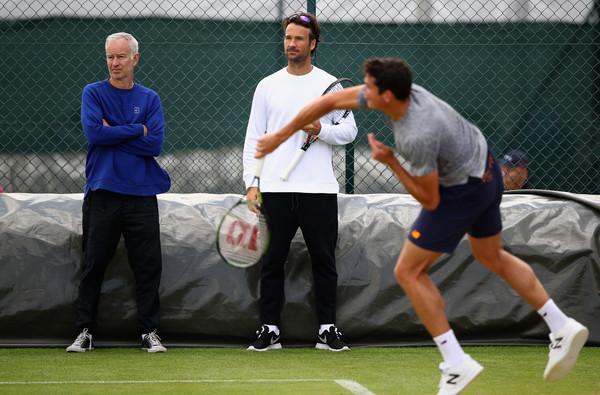 Supercoaches John McEnroe (left) and Carlos Moya (centre) look on during a practice with Milos Raonic (right, serving) at WImbledon in July. Photo: Clive Brunskill/Getty Images)