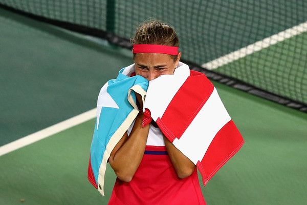 Monica Puig celebrates with the Puerto Rican flag around her shoulders after defeating Angelique Kerber in the women’s gold medal match on Day 8 of the Rio 2016 Olympic Games. | Photo: Clive Brunskill/Getty Images South America