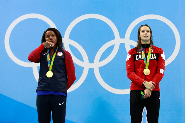 Simone Manuel (L) and Penny Oleksiak stand on the Olympic podium with their gold medals after both winning the women’s 200m freestyle final. | Photo: Adam Pretty/Getty Images South America