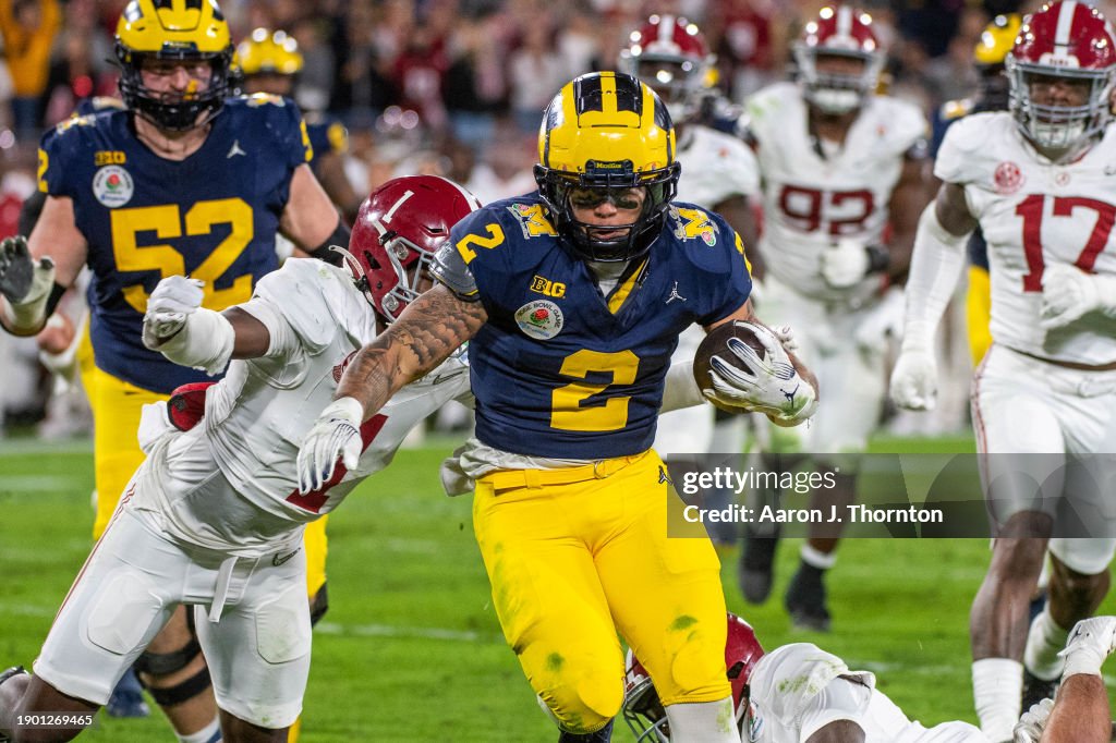 Blake Corum #2 of the Michigan Wolverines runs with the ball for yardage away from Kool-Aid McKinstry #1 of the Alabama <strong><a  data-cke-saved-href='https://www.vavel.com/en-us/ncaa/2022/03/26/college-basketball/1106446-2022-ncaa-tournament-hot-shooting-from-ryan-helps-notre-dame-upset-alabama.html' href='https://www.vavel.com/en-us/ncaa/2022/03/26/college-basketball/1106446-2022-ncaa-tournament-hot-shooting-from-ryan-helps-notre-dame-upset-alabama.html'>Crimson Tide</a></strong> during second half of the CFP Semifinal Rose Bowl Game at Rose Bowl Stadium on January 01, 2024 in Pasadena, California. The Michigan Wolverines won the game 27-20 in overtime. (Photo by Aaron J. Thornton/Getty Images)