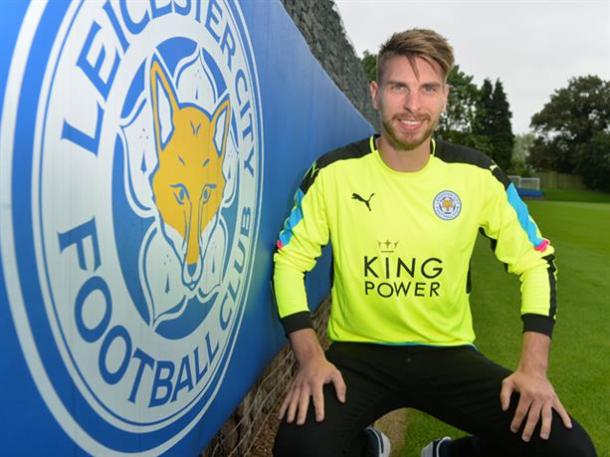 Zieler poses in his new shirt, beside the Leicester City crest. | Image credit: Plumb Images - Leciester City