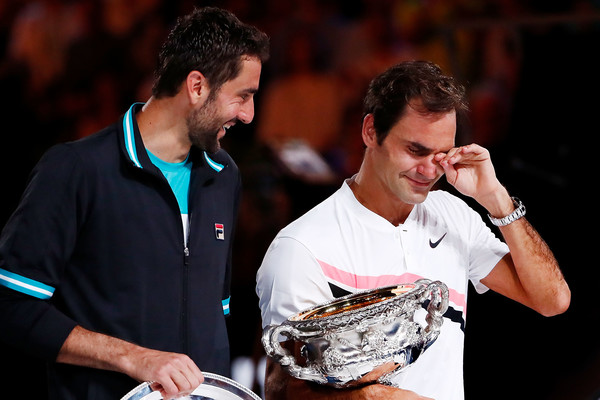 Marin Cilic (L) jokes around with an emotional Roger Federer during the trophy ceremony after battling in the 2018 Australian Open final. | Photo: Roger Federer celebrates after winning a point against Marin Cilic during the final of the 2018 Australian Open. | Photo: Michael Dodge/Getty Images