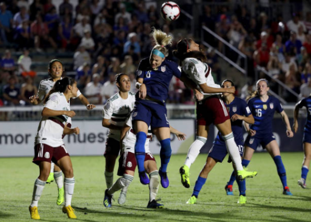 Julie Ertz (center) wins a header while surrounded by Mexican players. | Photo: Streeter Lecka - Getty Images