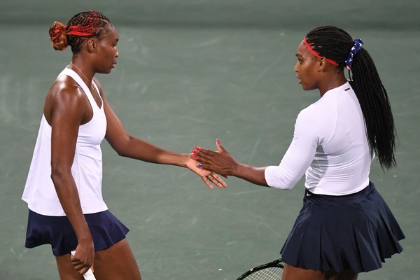Serena (R) and Venus Williams high-five in between points during their first round doubles match against Lucie Safarova and Barbora Strycova at the RIo 2016 Olympic Games. | Photo: Martin Bernetti/AFP