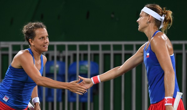 Lucie Safarova (R) and Barbora Strycova high-five in between points during their first round doubles match at the Rio 2016 Olympic Games. | Photo: Martin Bernetti/AFP