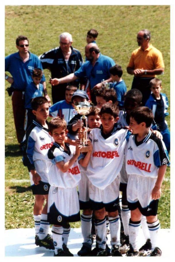 Roberto (davanti, a sinistra) e Andrea (davanti, al centro) sollevano un trofeo con la maglia dell'Atalanta.
