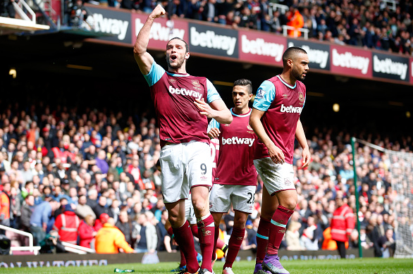 Carroll celebrates his side's second goal, whilst Arsenal fans are stunned into silence after a promising first 45. | Photo: Getty