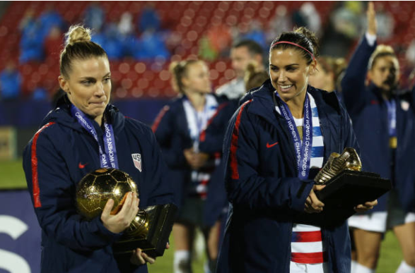 Julie Ertz (left) and Alex Morgan (right) carry their hardware after the USWNT won the 2018 CONCACAF Women's Championship. | Photo: Omar Vega - Getty Images