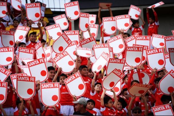 Con la campaña #AmorPorTuEscudoLeón, se repartieron escudos gigantes del equipo en todas las tribunas de 'El Campín'. Imagen: @SantaFe.