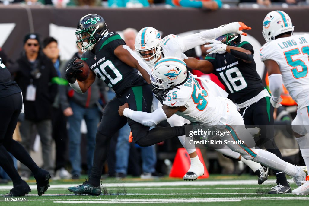 Running back Breece Hall #20 of the New York Jets runs and is tackled by linebackers Jaelan Phillips #15 and Cameron Goode #53 of the Miami Dolphins during a football game at MetLife Stadium on November 24, 2023 in East Rutherford, New Jersey. (Photo by Rich Schultz/Getty Images)