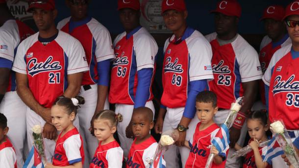 Members of the Cuban national baseball team wait in the dugout with children before the game. (Chip Somodevilla / Getty Images)