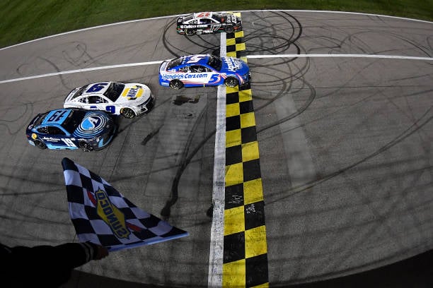 Kyle Larson, driver of the #5 HendrickCars.com Chevrolet, takes the checkered flag over Chris Buescher, driver of the #17 Castrol Edge Ford, to win the NASCAR Cup Series AdventHealth 400 at Kansas Speedway on May 05, 2024 in Kansas City, Kansas. (Photo by Logan Riely/Getty Images)