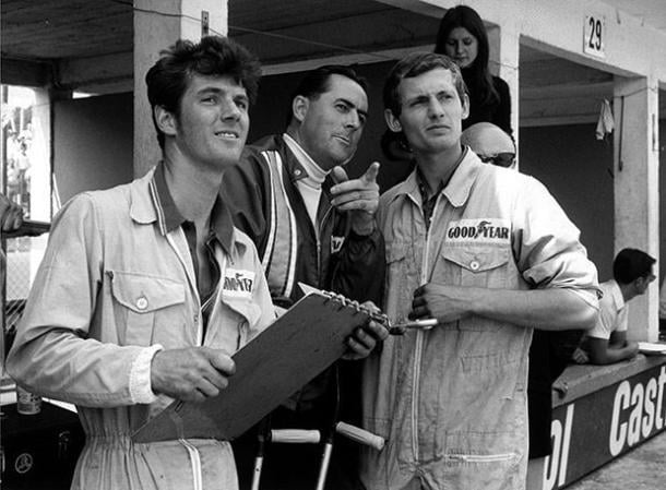 Dennis (R) started life as a mechanic, seen alongside Triple World Champion, Sir Jack Brabham (C) (Image Credit (Pinterest - unknown user) 