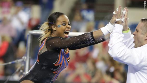 Kennedy Baker celebrates a stuck bar routine with Florida bars coach Adrian Burde at the NCAA Women's Gymnastics Championships/Erin Long