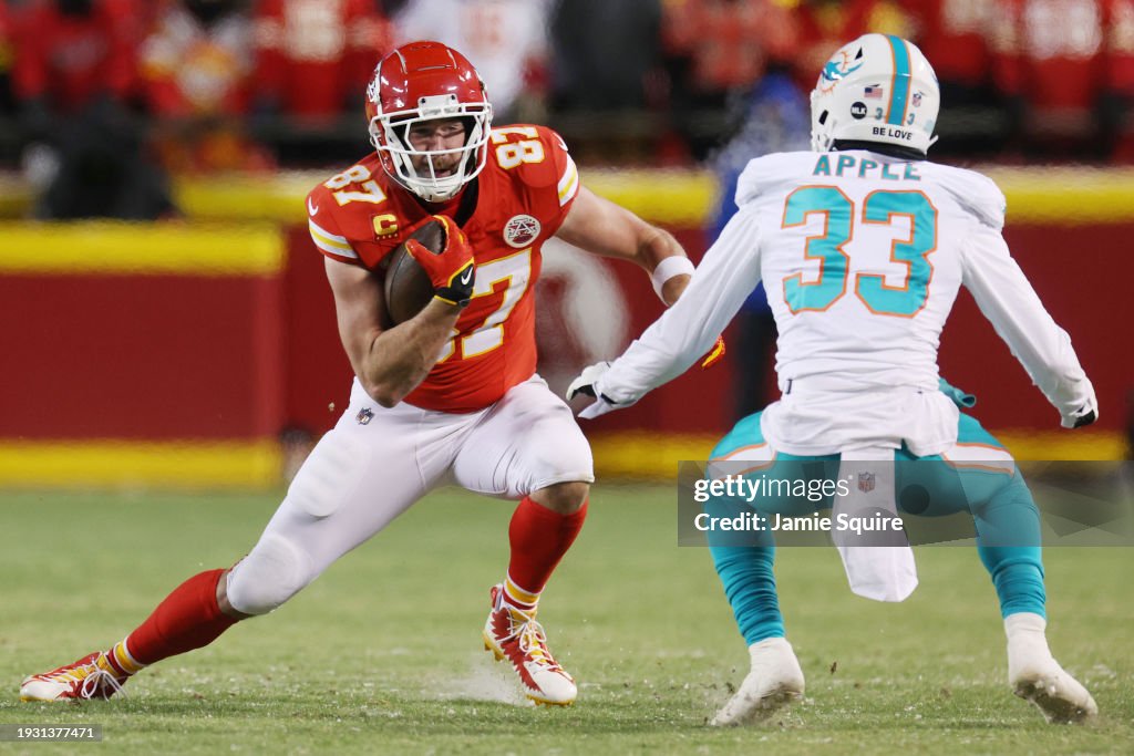 Travis Kelce #87 of the Kansas City Chiefs runs with the ball against Eli Apple #33 of the Miami Dolphins during the second half in the AFC Wild Card Playoffs at GEHA Field at Arrowhead Stadium on January 13, 2024 in Kansas City, Missouri. (Photo by Jamie Squire/Getty Images)