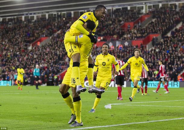 Ayew leaps on Lescott in celebration after Villa take the lead (photo: PA)