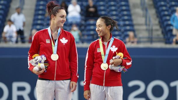 Gabriela Dabrowski and Carol Zhao wait on the podium after receiving their gold medals after winning the women’s doubles competition at the Toronto 2015 Pan American Games. | Photo via the Canadian Olympic Committee