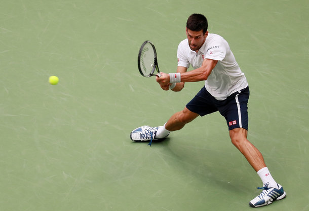 Djokovic slides into a backhand (Photo by Michael Reaves/Getty Images)