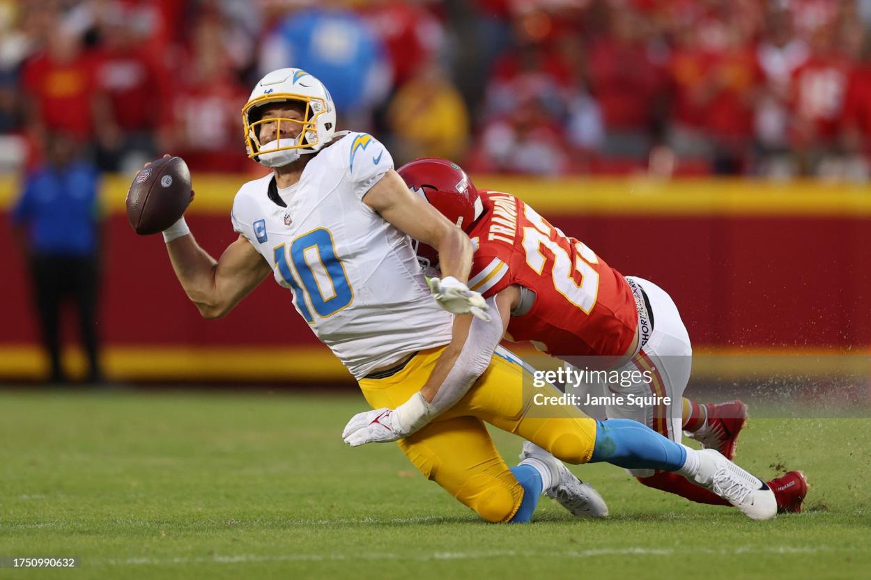 Justin Herbert #10 of the Los Angeles Chargers is sacked by Drue Tranquill #23 of the Kansas City Chiefs during the fourth quarter at GEHA Field at Arrowhead Stadium on October 22, 2023 in Kansas City, Missouri. (Photo by Jamie Squire/Getty Images)