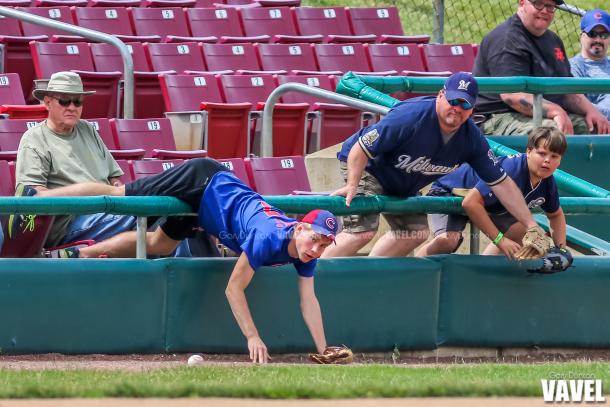 Fans attempt to field a ground ball from the stands during MiLB baseball game between the Kane County Cougars - the Wisconsin Timber Rattlers at Fifth Third Bank Ballpark in Geneva, IL June 12, 2016