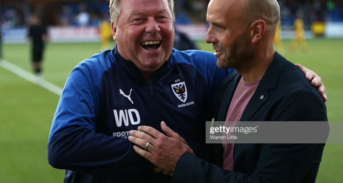Managers Wally Downes, of AFC Wimbledon and Paul Tisdale of MK Dons share a laugh ahead of kick off in the Carabao Cup First Round match between AFC Wimbledon and Milton Keynes at The Cherry Red Records Stadium on August 13. (Photo by Warren Little/Getty Images)