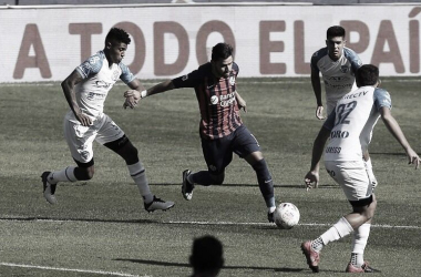 Ángel Romero (azul) con el balón ante la marca de 3 jugadores del Tomba (blanco). Fuente: Web.